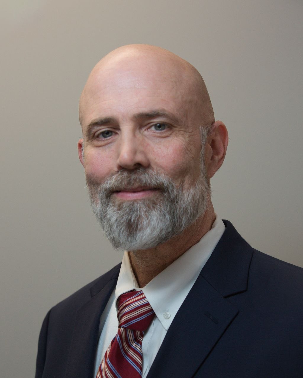 Professional headshot — man with beard and red striped tie