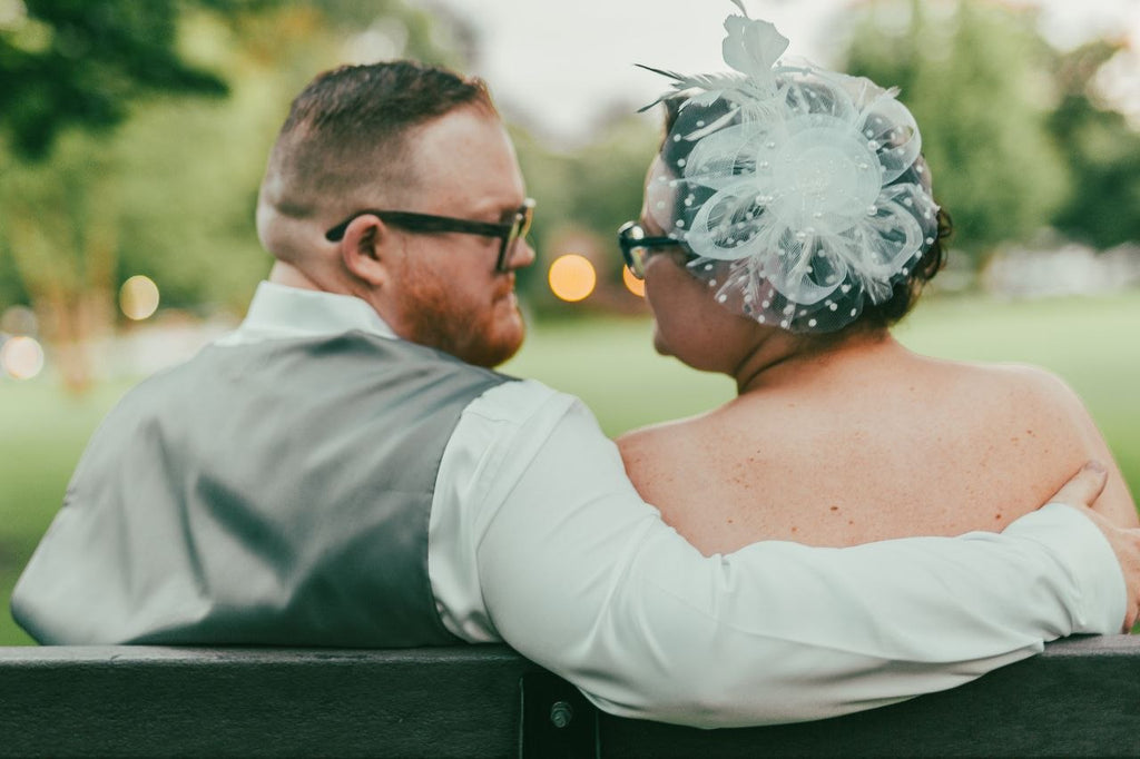 Bride and groom on a park bench at dusk with warm bokeh lights