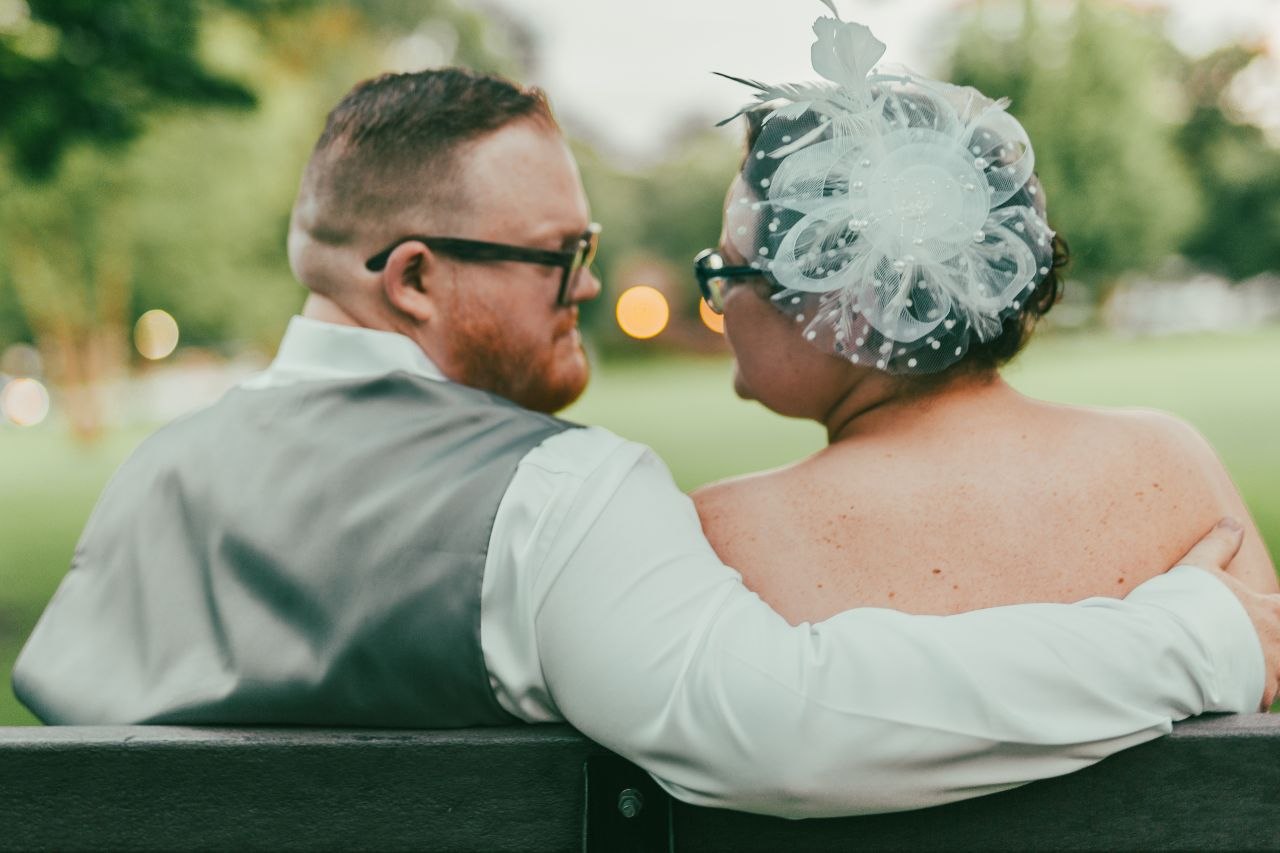 Bride and groom on a park bench at dusk with warm bokeh lights