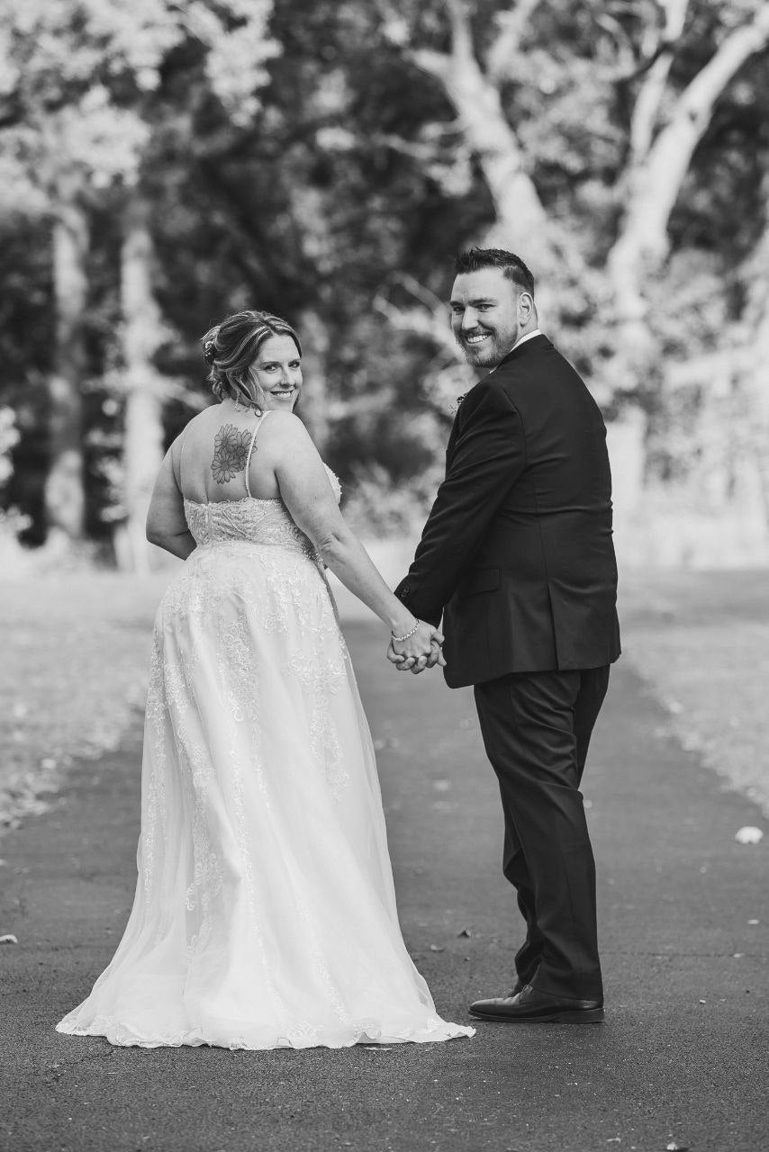 Bride and groom walking away looking back over shoulders, black and white