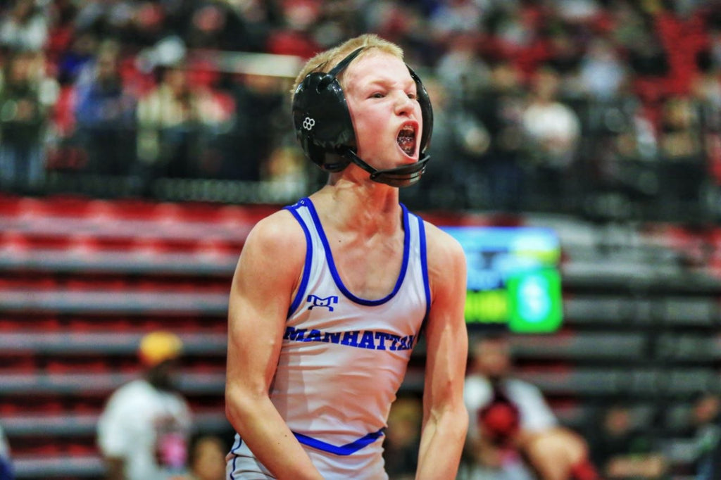 Manhattan wrestler in white singlet roaring during match
